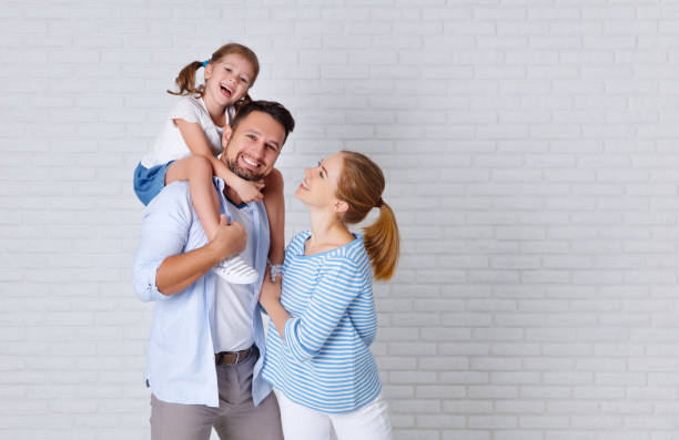 happy family mother father and child  near an empty brick wall happy family mother father and child daughter near an empty brick wall family photo on wall stock pictures, royalty-free photos & images