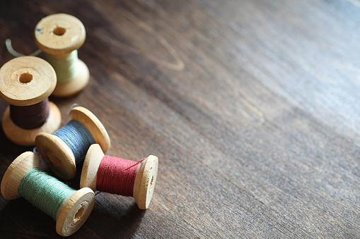 Sewing thread on a wooden background. Set of threads on bobbins retro style. Vintage accessories for sewing on the table