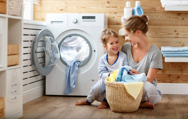 szczęśliwa matka rodzinna gospodyni domowa i dziecko w pralni z pralką - stereotypical housewife little girls family domestic kitchen zdjęcia i obrazy z banku zdjęć