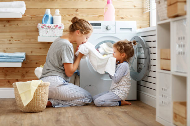 ama de casa feliz madre de familia y el niño en la lavandería con lavadora - stereotypical housewife little girls family domestic kitchen fotografías e imágenes de stock