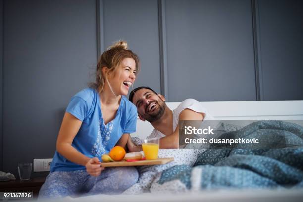 Beautiful Happy Young Romantic Girl Brings Breakfast To Her Husband In The Bed And Laughing Together After He Wakes Up Stock Photo - Download Image Now