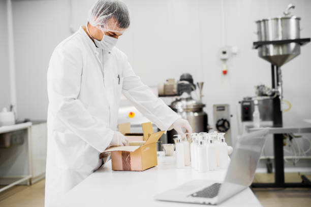 istock Protected scientist packing cosmetics products from a lab table near a laptop. 921367976