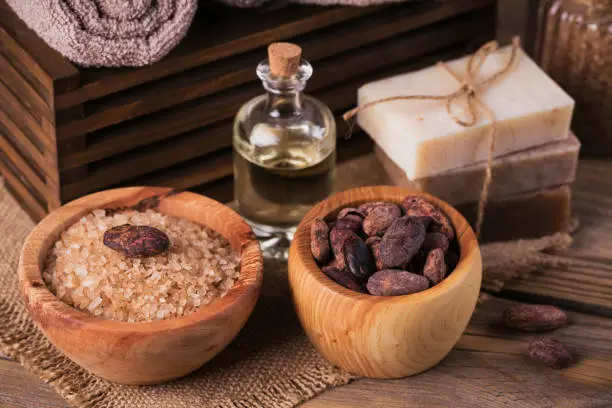 Natural cosmetic oil, sea salt and natural handmade soap with cocoa beans on rustic wooden background. Healthy skin care. SPA concept. Close up