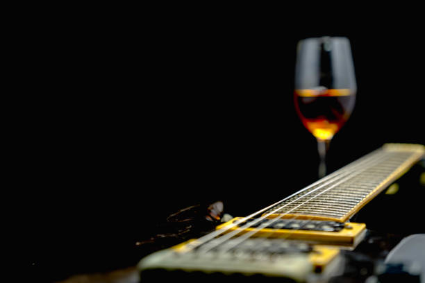 Guitar and whiskey glass on black background