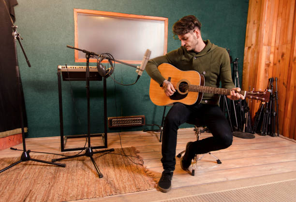 Man playing guitar in recording studio Man playing guitar in recording studio wide shoot acoustic guitar tattoos stock pictures, royalty-free photos & images