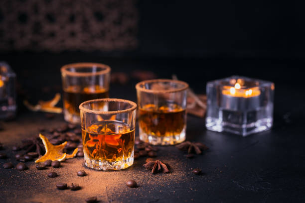 Whiskey, brandy or liquor, spices, anise stars, coffee beans, cinnamon sticks Whiskey, brandy or liquor, coffee beans, spices and decorations on dark background. Seasonal holidays concept. coffee liqueur stock pictures, royalty-free photos & images