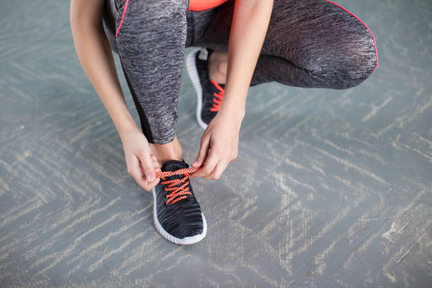 istock young woman runner tying shoelaces 921386798