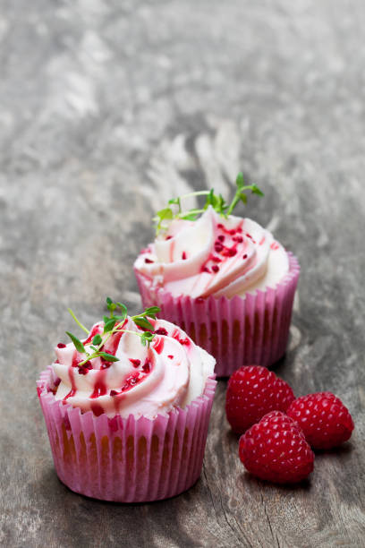 istock Cupcakes  with fresh raspberries and cream on wooden table 921424290