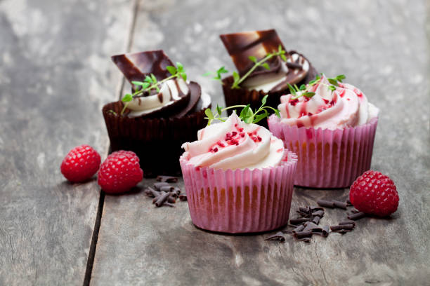 istock Chocolate  cupcakes with fresh raspberries and cream on wooden table 921427206