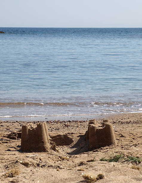 istock sand castle on the beach with two towers an ocean 92142883