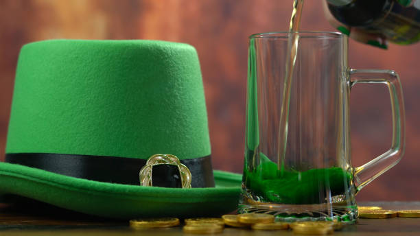 istock St Patrick's Day pouring green beer with green leprechaun hat 921432324