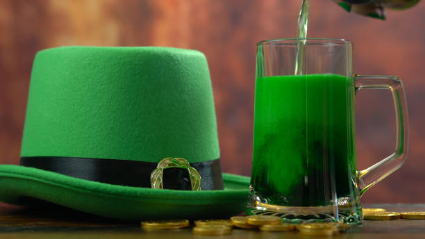 istock St Patrick's Day pouring green beer with green leprechaun hat 921432340