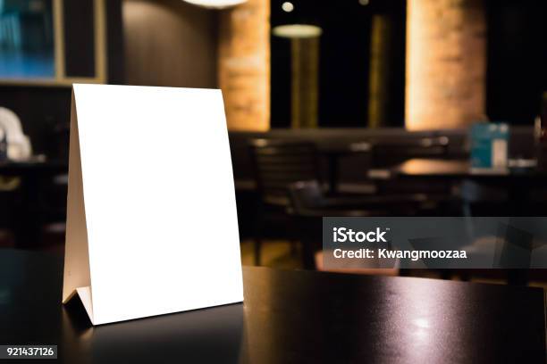 Mockup White Label Menu Frame On Table With Cafe Restaurant Interior Background Stock Photo - Download Image Now