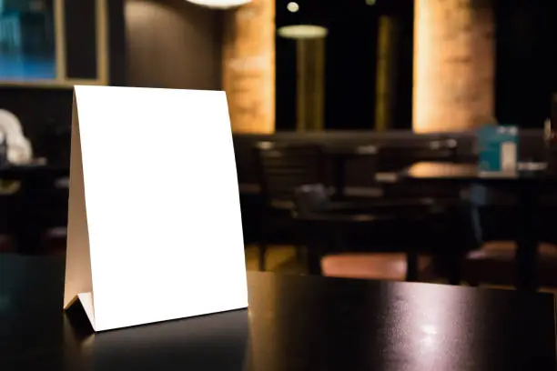 Mockup empty white label menu frame on table with cafe restaurant interior background