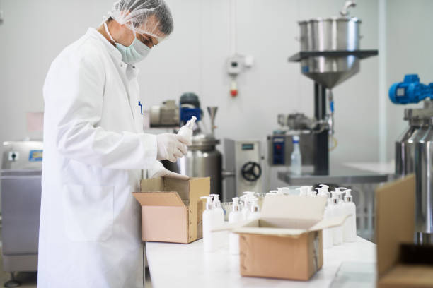 istock Cosmetics fabric worker taking one liquid soap from a row and putting in a paper box for transport. 921438068