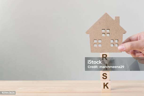 Property Investment And House Mortgage Financial Risk Management Concept Hand Putting Wooden Home On Wood Block With Word Risk Stock Photo - Download Image Now