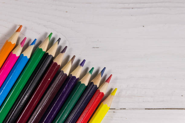 istock Colored pencils on white wooden desk. Top view, copy space 921472322