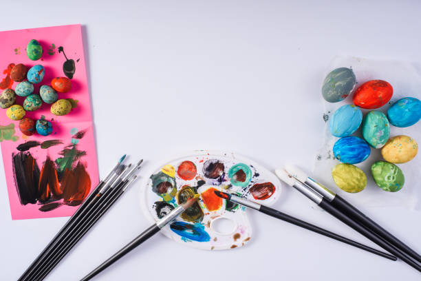 istock Painted chicken and quail easter eggs, brushes and paints on white background 921480952