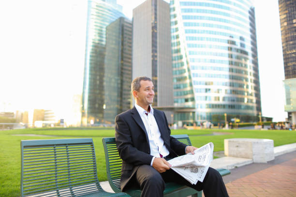 istock Gladden male manager reading newspaper outside in 921486410