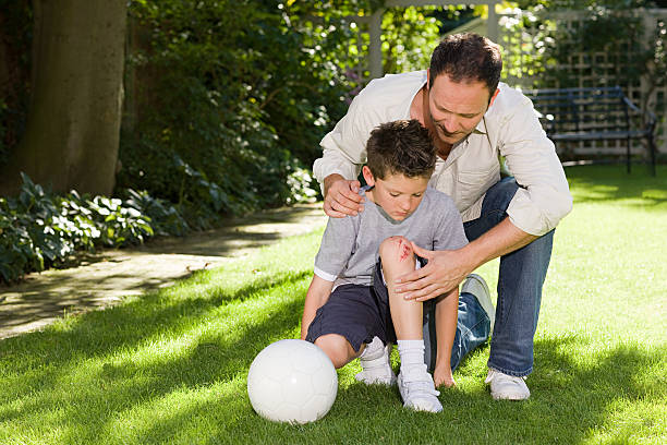 Father and son with a grazed knee  scraping stock pictures, royalty-free photos & images