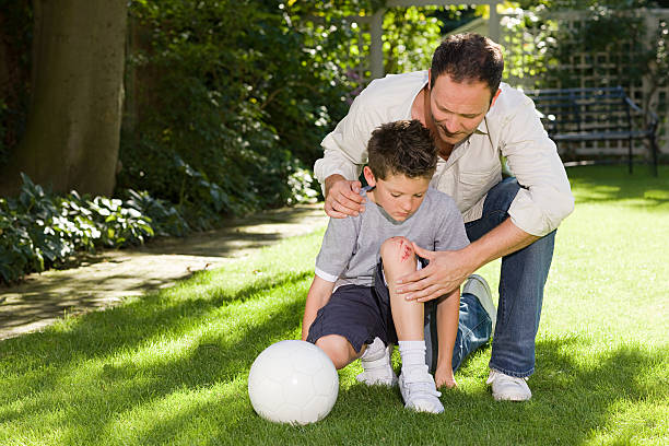 father and son with a grazed knee - scraping стоковые фото и изображения