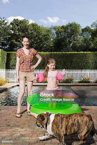 Mother And Daughter With Dog By Swimming Pool — стоковые фотографии и другие картинки 20-24 года - 20-24 года, 8-9 лет, Бассейн