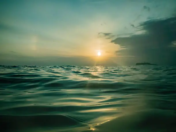 Photo of Wind waves on the surface of the ocean, reflecting the sunset
