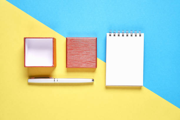 istock Red gift box,and empty notebook on pastel background, Free space on the notebook for placing text. 921498380