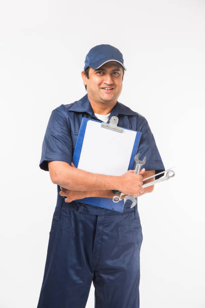 istock Indian happy auto mechanic in blue suit and cap holding spanner tool in action, isolated over white background 921509388