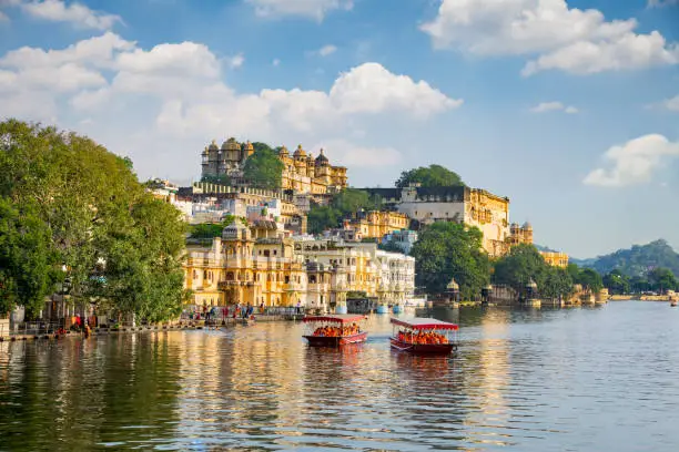 Photo of City Palace and tourist boat on lake Pichola. Udaipur, Rajasthan, India