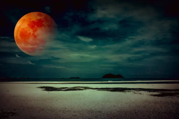 Beautiful fantasy tropical beach of seascape in night. Attractive red super moon or blood moon on dark sky with cloud. Serenity nature background. Vintage filter effect. The moon taken with my camera.