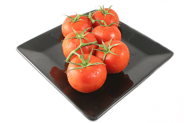 Vine tomates aislado en una placa negra - foto de stock