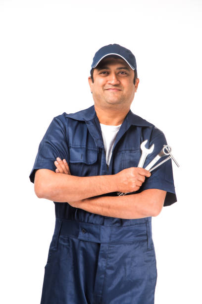 istock Indian happy auto mechanic in blue suit and cap holding spanner tool in action, isolated over white background 921521516