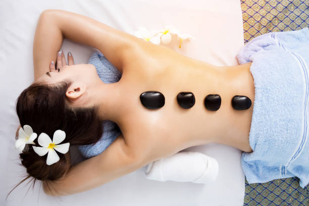 Hot stone on back of asian pretty woman in spa room Top view of back of pretty asian woman lying on spa bed and have hot stone laying on her back, body and skin treatment in relaxation time, spa concept hot stone massage stock pictures, royalty-free photos & images