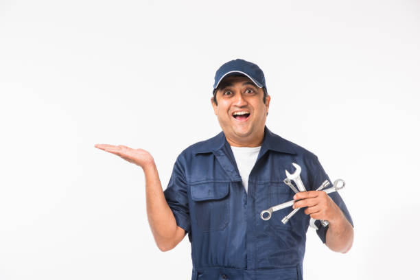 istock Indian happy auto mechanic in blue suit and cap holding spanner tool in action, isolated over white background 921532026