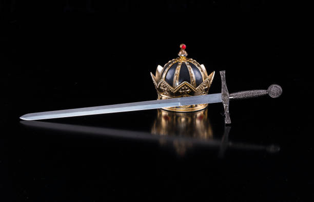istock Medieval sword and crown on a black isolated background 921543728