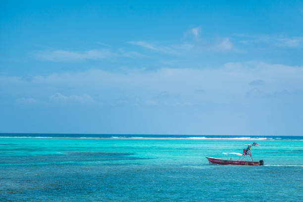 маленькая моторная лодка в мелкой воде возле пляжа на стороне туристов острова - fishing nautical vessel small men стоковые фото и изображения