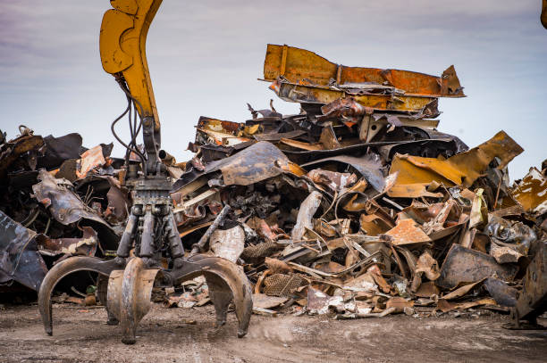 excavadora de orugas grandes trabajando una pila de acero en un metal reciclar yarda, francia - chatarra fotografías e imágenes de stock