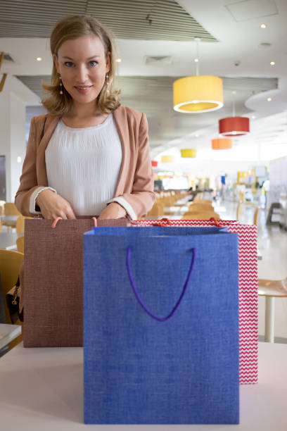 istock Content Lady with Bags on Table in Shopping Center 921566370