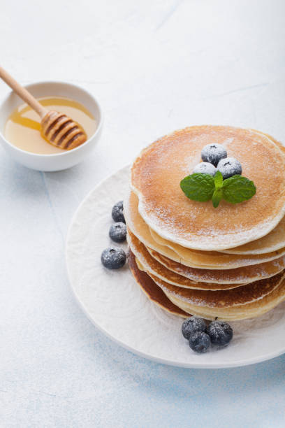 istock A stack of delicious pancakes with honey and blueberries on a light blue background 921570954