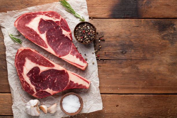 istock Two fresh raw marble meat, black Angus ribeye steak with spices on a old rustic table. Raw beef on a wooden background. Top view with copy space 921571052