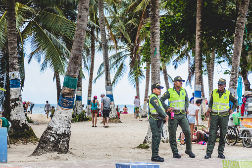 SAN ANDRES ISLAND, Colombia _ Circa March 2017.  Policemen, Beach, Palm Trees and few People Walking on the Sand on San Andres Island, Colombia.