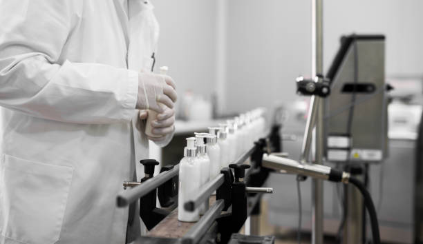 istock Cosmetics fabric worker taking one liquid soap from a row on a fabric line. 921578080