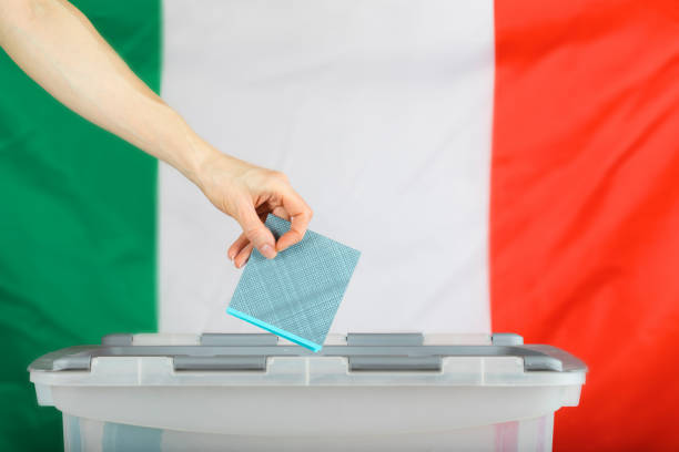 Female hand keeps ballot over ballot box.