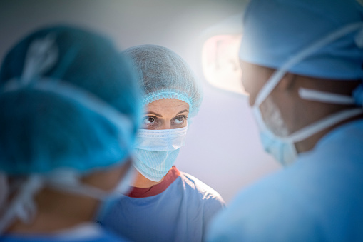 Team of doctors are standing in emergency room. Multi-ethnic surgeons are working at operating room at hospital. They are wearing blue scrubs.