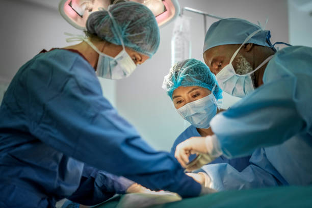 Multi-ethnic doctors operating girl at hospital Team of doctors are performing surgery on a patient at hospital. Multi-ethnic surgeons are operating patient in emergency room. They are wearing blue scrubs. operating room photos stock pictures, royalty-free photos & images