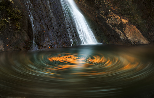 Long exposure image of a waterfall and autumn leaves circulating in the pond of waterfall. Captured in Nebiler, Izmir