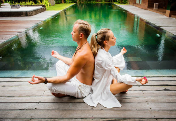 istock Couple meditate together by the pool 921587836