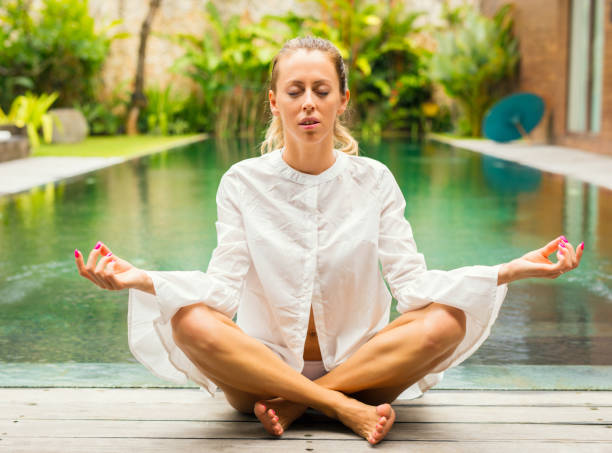 istock Woman meditate by the pool 921587878