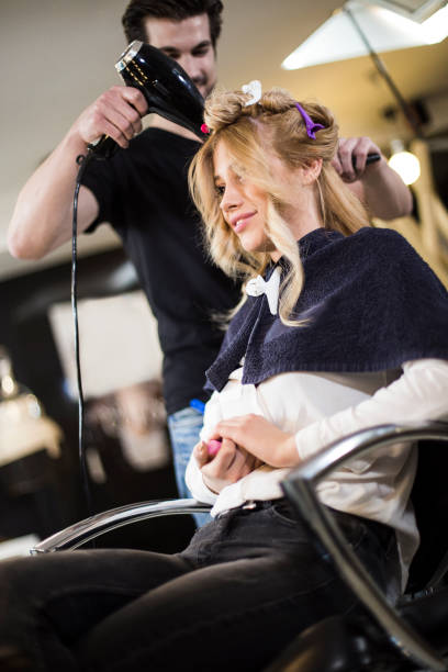 istock Hairdresser using hairdryer on a customer 921590784